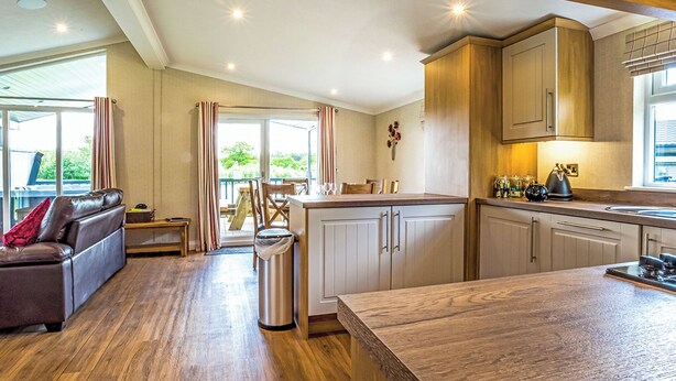 Une cuisine moderne avec des meubles en bois, un coin repas comprenant une table et des chaises, et un canapé en cuir.