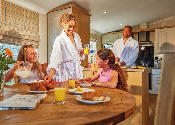 Un desayuno familiar en una cocina moderna con armarios de madera, una mesa de comedor y una encimera.