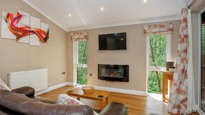 A living room with a brown leather sofa, a wooden coffee table, a flat-screen TV, and a fireplace. - Cosy log cabin with one double. (Freehay, Cheadle)