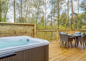A wooden deck with a hot tub, wicker furniture, and a view of trees. - 1 bedroom accommodation in Haddon (Haddon)