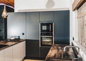 A modern kitchen with a built-in oven, a microwave, and a stainless steel sink.