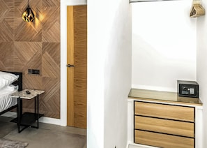 A bedroom with a bed, bedside table, lamp, and a wooden door. - Four bed lodge with three king-size beds and one twin (king by arrangement). (Nottingham)