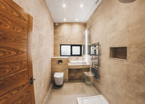 A modern bathroom with a wooden door, a toilet, a sink, a mirror, and a towel rack. - Four bed lodge with three king-size beds and one twin (king by arrangement). (Nottingham)