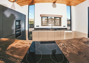 A modern kitchen with a built-in oven, a large window, and a unique black countertop. - Four bed lodge with three king-size beds and one twin (king by arrangement). (Nottingham)