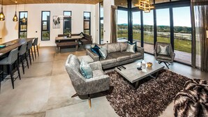 A spacious living area with a large window, a dining table, and seating arrangements. - Four bed lodge with three king-size beds and one twin (king by arrangement). (Nottingham)