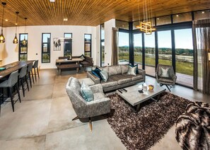 A spacious living area with a large window, a dining table, and seating arrangements. - Four bed lodge with three king-size beds and one twin (king by arrangement). (Nottingham)