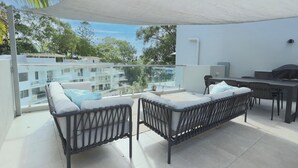 A balcony with two wicker sofas, a dining table, and a grill. - Penthouse 22  - The Cove (Noosa Heads)