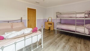 A room with a bunk bed, a single bed, a desk, and a door. - 1 bedroom accommodation in Crimdon (Crimdon)
