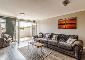 A living room with a sofa, a coffee table, and a painting on the wall. - 1 bedroom accommodation in Crimdon (Crimdon)