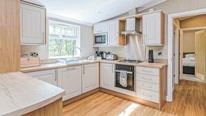 Una cucina compatta con mobili bianchi, un forno a microonde, un fornello e una finestra.