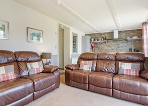 A living room with a brown leather sofa, a lamp, and a fireplace.