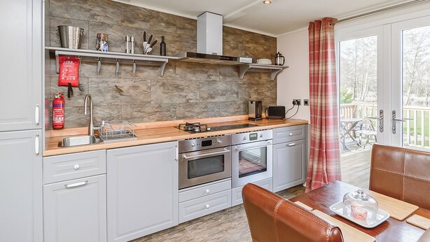 A modern kitchen with a stone backsplash, stainless steel appliances, and a dining area with a table and chairs.