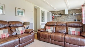 A living room with a brown leather sofa, a lamp, and a fireplace.