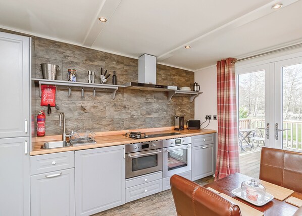 A modern kitchen with a stone backsplash, stainless steel appliances, and a dining area with a table and chairs.