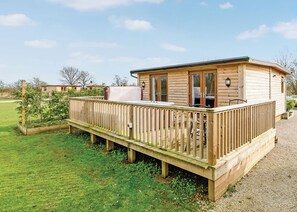 Eine Holzhütte mit einer Terrasse, einem überdachten Sitzbereich und einem sichtbaren Fenster.
