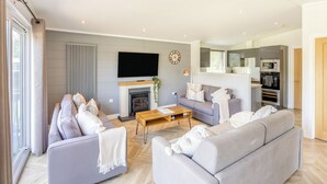 A modern living room with a fireplace, grey sofas, a coffee table, and a TV. - Lakeview Premier Pet Friendly (Woodhall Spa)
