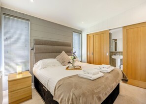 Une chambre d’hôtel avec un grand lit, une table de chevet, une armoire en bois et une salle de bain équipée d’un lavabo et d’un miroir.