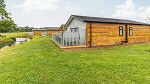Une rangée de cabanes en bois, avec une pelouse verdoyante et un petit ruisseau.