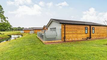 Une rangée de cabanes en bois, avec une pelouse verdoyante et un petit ruisseau.