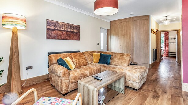 Un salon moderne avec un canapé d’angle, une table basse en bois et un lampadaire.