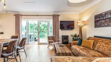 Un salon comprenant un canapé, un téléviseur, une cheminée et un coin repas avec des chaises et une table.