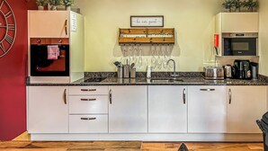 Een moderne keuken met een inbouwoven, magnetron en koffiezetapparaat, plus een spoelbak en diverse keukengerei.