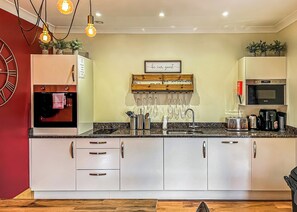 A modern kitchen with a built-in oven, microwave, and coffee maker, along with a sink and various utensils. - 3 bedroom accommodation in Flaxton (Flaxton)
