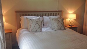 A bed with a wooden headboard, two bedside tables, and a lamp on one of the tables. - Boutique and spacious luxury lodge, perfect for a romantic escape. (West Tanfield)