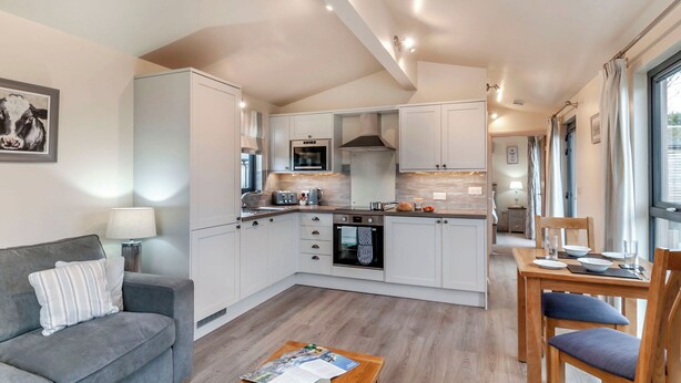 A compact kitchen with modern appliances, a dining area with a table and chairs, and a cozy seating area with a sofa and a lamp. - Boutique and spacious luxury lodge, perfect for a romantic escape. (West Tanfield)
