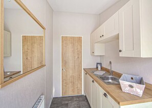 A compact kitchen with a wooden door, a sink, and cabinets. - Brand new for 2021 a complete home from home with 2 double bedrooms. (Skegness)