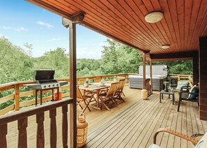 A wooden deck with a grill, table, chairs, and a hot tub. - 3 bedroom accommodation in Caerwys, Flintshire (Caerwys, Flintshire)