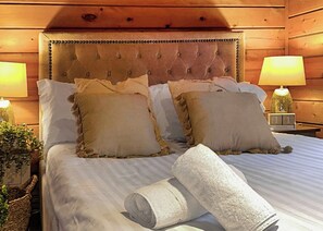 A neatly made bed with a tufted headboard, two bedside lamps, and a clock on the nightstand. - 3 bedroom accommodation in Caerwys, Flintshire (Caerwys, Flintshire)