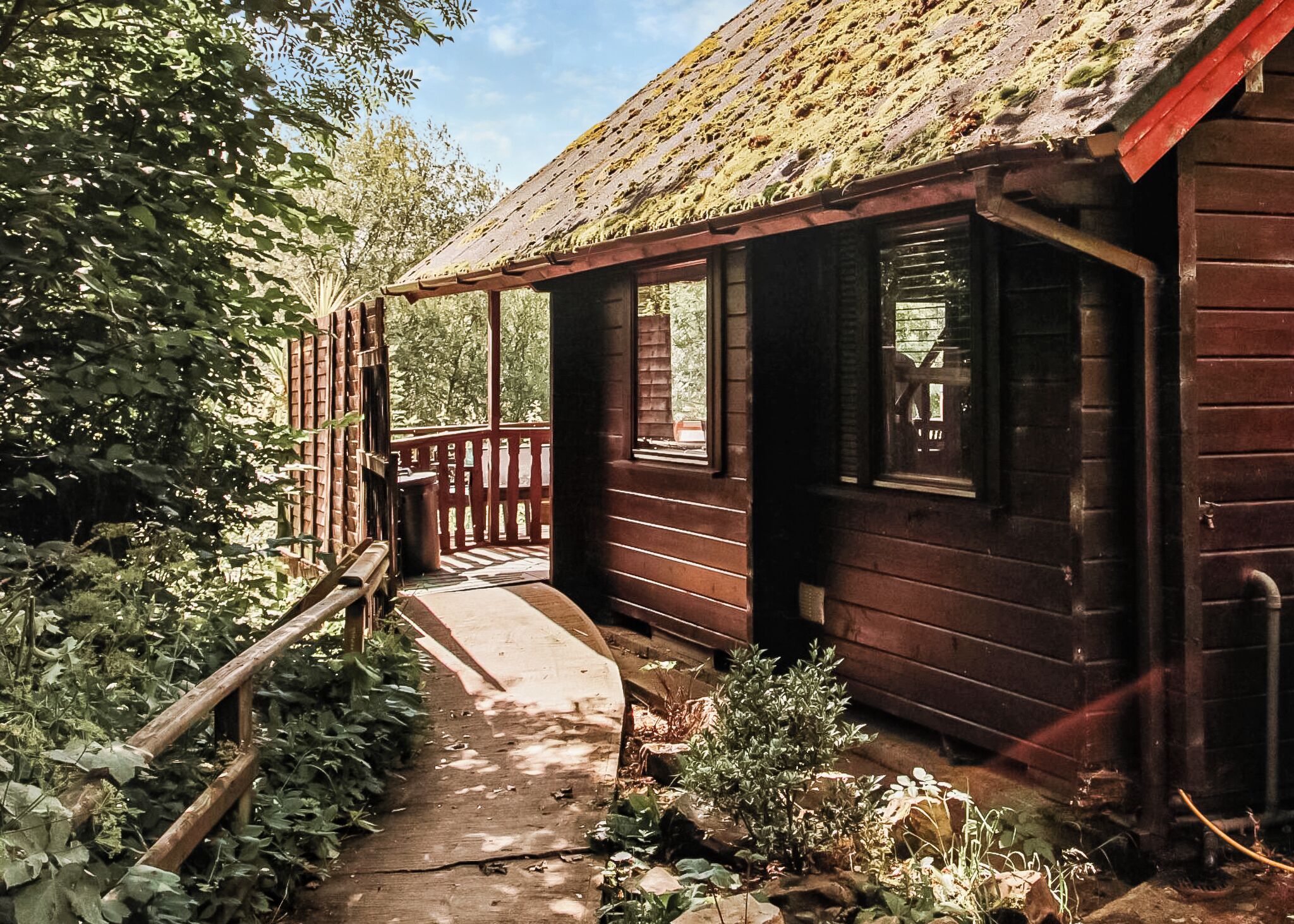 Un chalet rustique doté d’un porche en bois, d’une petite fenêtre et d’un sentier menant à l’entrée.