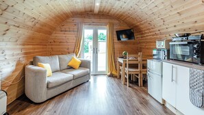A cozy cabin with a wooden interior, a sofa, a dining table, and a kitchenette.