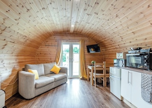 A cozy cabin with a wooden interior, a sofa, a dining table, and a kitchenette. - Here at Riverview our hot tub pods have been warming up. (Newcastleton,)
