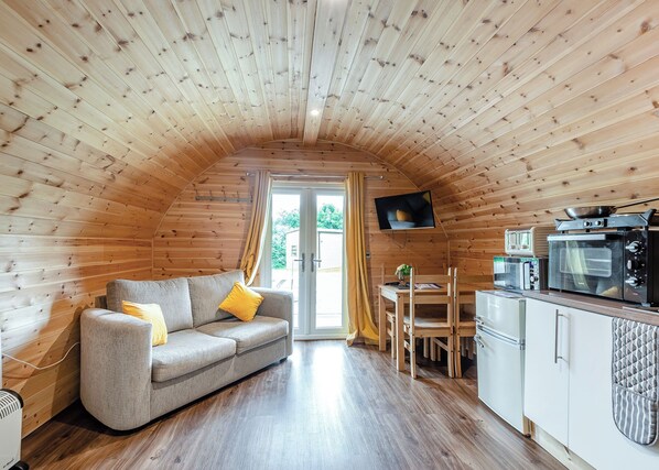 Ein gemütliches Blockhaus mit Holzvertäfelung, einer Couch, einem Esstisch und einer Küchenzeile.