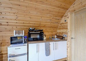A compact kitchen with a microwave, toaster, and stove, wooden walls, and a white cabinet. - Here at Riverview our hot tub pods have been warming up. (Newcastleton,)