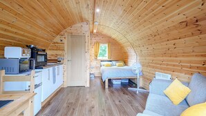 A cozy, wooden interior with a kitchenette, a bed, and a seating area.