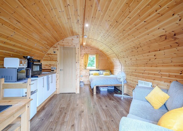 A cozy, wooden interior with a kitchenette, a bed, and a seating area. - Here at Riverview our hot tub pods have been warming up. (Newcastleton,)