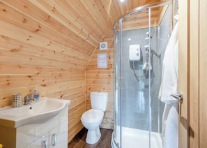 A wooden-paneled bathroom with a glass shower enclosure, a white sink, and a toilet. - Here at Riverview our hot tub pods have been warming up. (Newcastleton,)