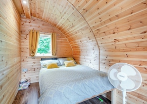 A cozy wooden room with a bed, a window with curtains, and a standing fan. - Here at Riverview our hot tub pods have been warming up. (Newcastleton,)