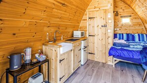 A cozy cabin interior with a kitchenette, a bed, and a small window.