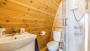 A bathroom with a wooden wall, a sink, a toilet, and a shower with a glass door.