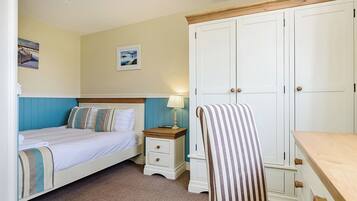 Une chambre à coucher avec un lit, une table de chevet, une lampe, une chaise, une armoire et un tableau au mur.