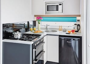 Uma cozinha moderna com fogão, forno, micro-ondas, pia e máquina de lavar louça.