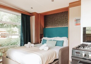 Quarto de hotel com cama, janela com cortinas, fogão e sinal de emergência contra incêndio.