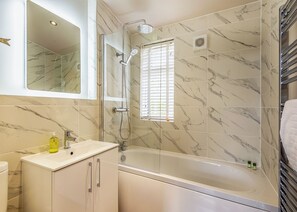 A bathroom with a bathtub, a shower, a vanity with a mirror, and a window with blinds. - New in 2021 Modern and luxurious lodge with lakeside view. (Woodhall Spa)
