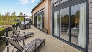 En moderne terrasse med udendørs møbler i flet, grill og store skydedøre.