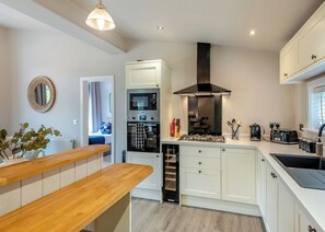 A modern kitchen with white cabinets, a built-in oven, a gas stove, and a window.