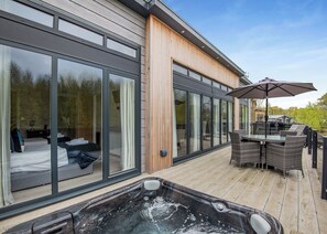 A modern building with large sliding glass doors, a hot tub, and outdoor furniture.